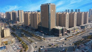 A high-rise building with a modern design, surrounded by other tall buildings and a busy intersection. - The Hotel V  Huai'an  University Town (Huai'an)