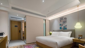 A modern hotel room with a large bed, bedside table, and a desk with a chair. - The Hotel V  Huai'an  University Town (Huai'an)