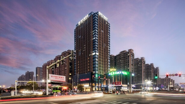 A high-rise building with multiple floors and a prominent sign at the top. - The Hotel V  Huai'an  University Town (Huai'an)