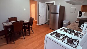 Una cocina compacta con estufa a gas, refrigerador y comedor con sillas y mesa.