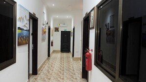A hallway with patterned flooring, doors, and artwork on the walls. - Wepia Guest House (Oyibi)