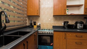 A modern kitchen with wooden cabinets, a stainless steel sink, a blue oven, and a coffee maker. - Wepia Guest House (Oyibi)