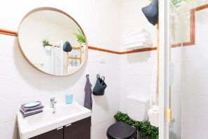 A bathroom with a round mirror, white sink, and a toilet. - Live in the heart of Surry Hills - walk to City (Surry Hills)