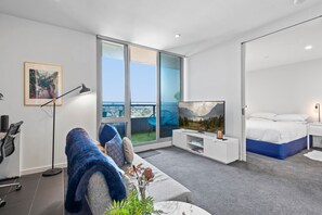 Een moderne hotelkamer met een groot raam, een bed, een televisie en een sofa.