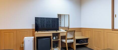 A hotel room with a bed, a desk with a television, a refrigerator, a microwave, and a chair.