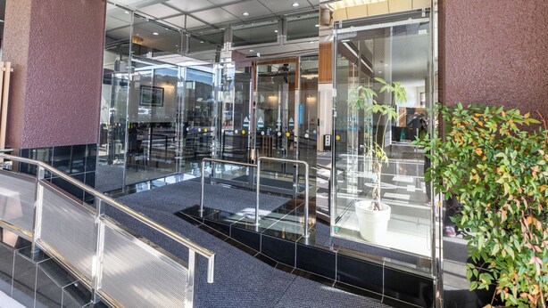Eine moderne Hotelhalle mit Glastür, Metallgeländern und einem Blumentopf.
