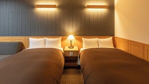 Ein Hotelzimmer mit zwei Betten, einem Nachttisch mit Lampe und einer Wand mit Muster.