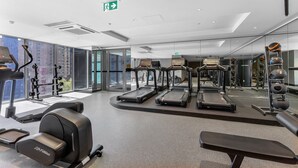 Un gimnasio moderno con cintas de correr, máquinas de pesas y un banco.