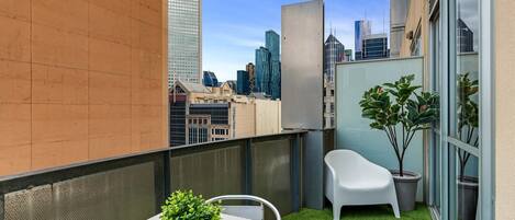 A balcony with a small table, chairs, and potted plants.