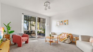 Una sala moderna con sofá, sillón, mesa de centro y vistas a un área exterior a través de una puerta corrediza de vidrio.
