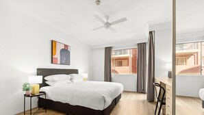 A modern hotel room with a large bed, a desk, and a view of the city. - Bright Inner-West Stay with Pool Access (Camperdown)