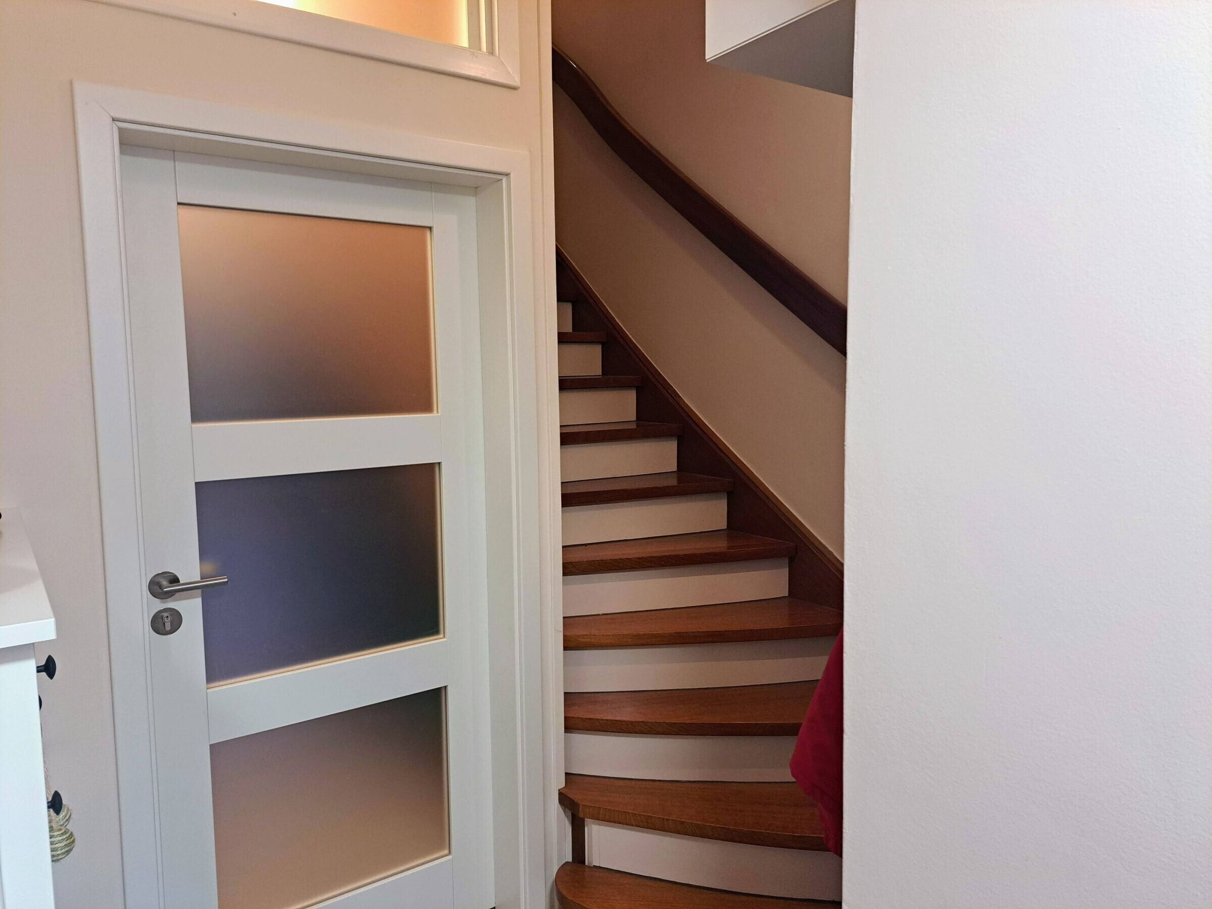 Une porte blanche avec des panneaux en verre dépoli et une poignée moderne.
