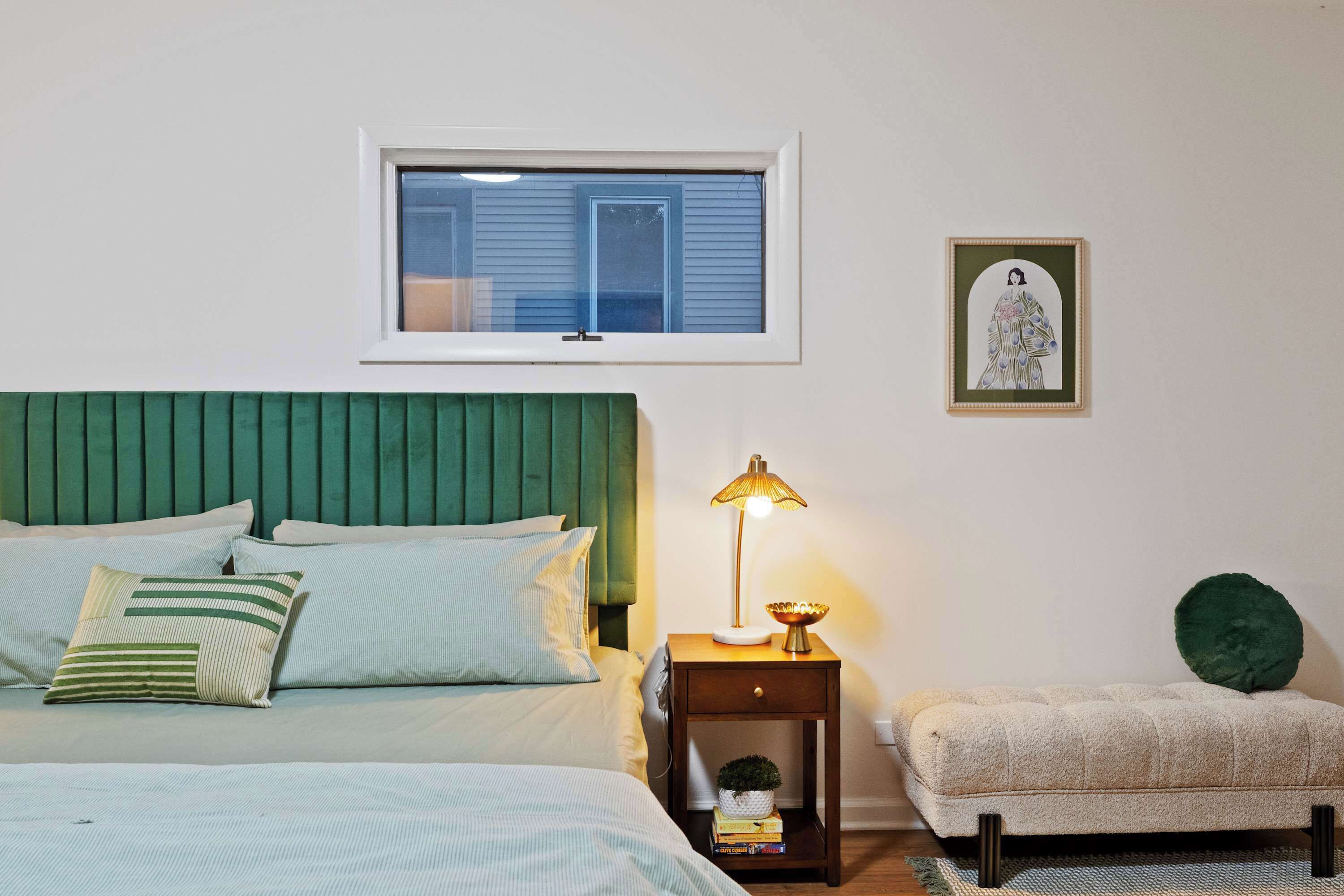 Une chambre à coucher avec un lit, une table de chevet, une lampe et une petite chaise.