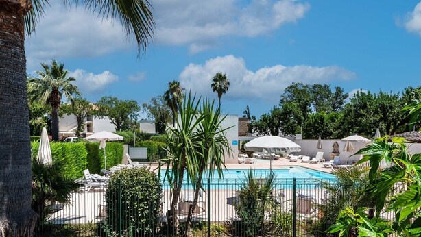 A pool area with lounge chairs and umbrellas, surrounded by palm trees and a clear sky. - Waterfront Riviera Charm with a View (Mandelieu-la-Napoule)