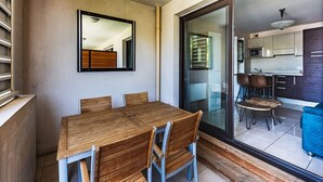 A dining area with a wooden table and chairs, a sliding glass door leading to a kitchen, and a view of the outside. - Waterfront Riviera Charm with a View (Mandelieu-la-Napoule)