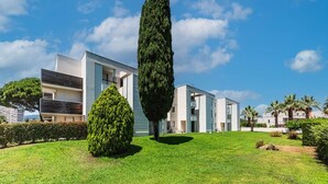 A modern residential building with a flat roof, multiple balconies, and a well-maintained lawn with a tall tree. - Waterfront Riviera Charm with a View (Mandelieu-la-Napoule)