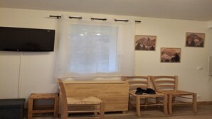 A room with a bed, two wooden chairs, a small table, a TV mounted on the wall, and three framed pictures on the wall. - Alpine Nook in the Heart of Allos (Allos)