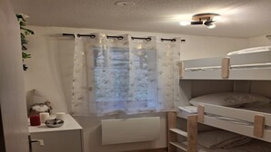 A small, well-lit room with a bunk bed, a desk with a lamp, and a window with a curtain. - Alpine Nook in the Heart of Allos (Allos)