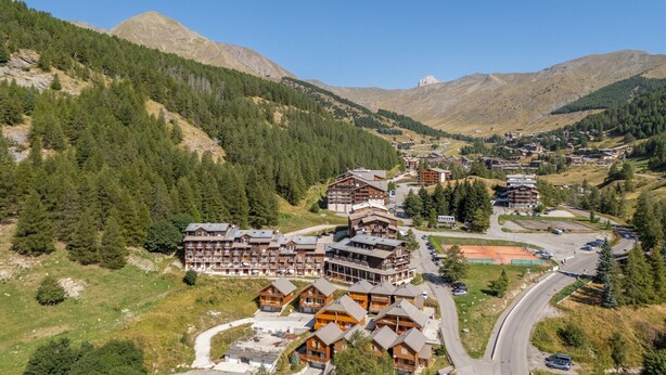 A mountainous resort with multiple wooden buildings, a winding road, and a clear view of the surrounding hills. - Alpine Nook in the Heart of Allos (Allos)