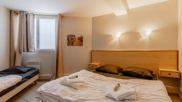 Una habitación de hotel con cama, mesita de noche, cortinas y una lámpara de pared.
