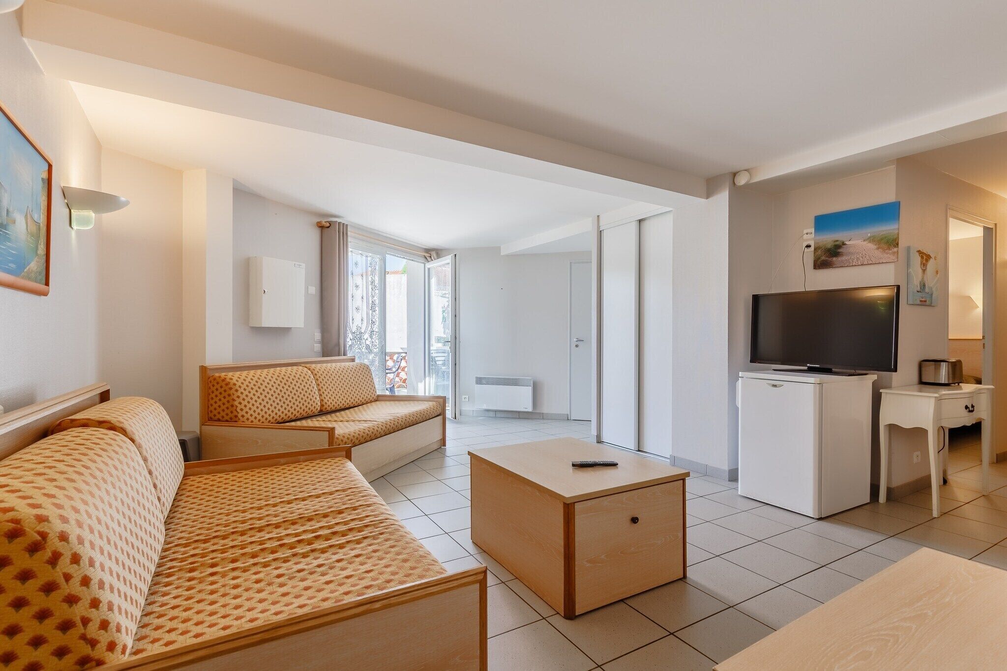 A modern living room with a sofa, a coffee table, a TV, and a mini-fridge.