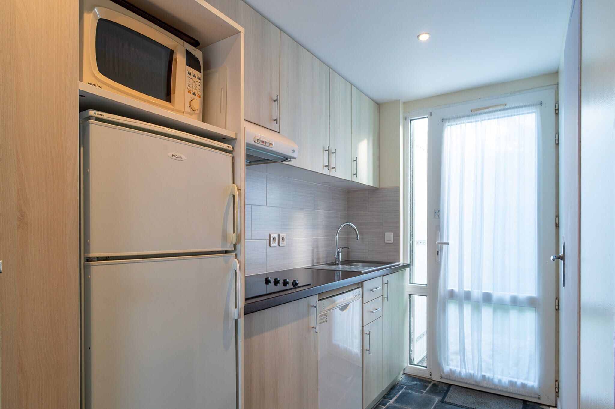 Una cocina moderna con microondas, refrigerador y lavamanos.