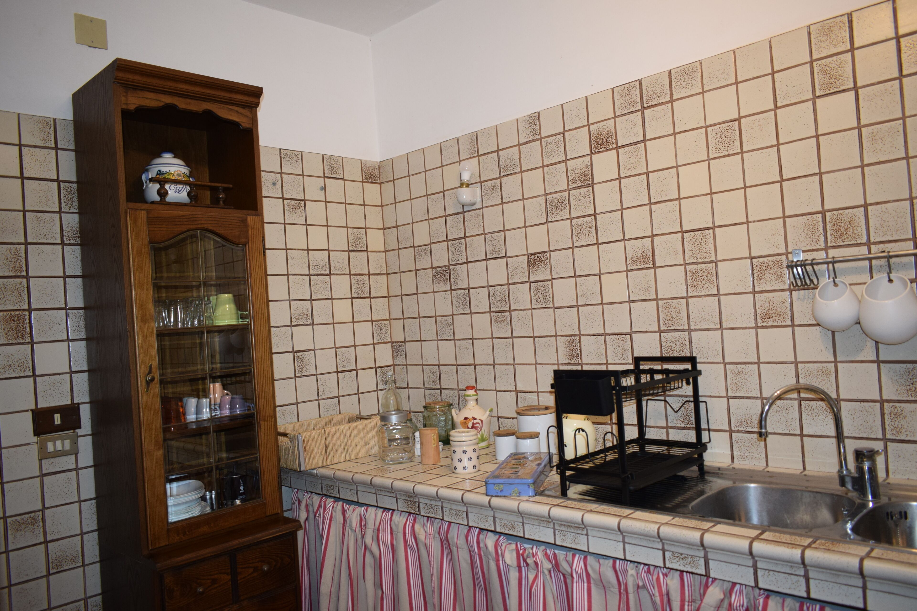 A kitchen with a wooden cabinet, tiled backsplash, and a sink.
