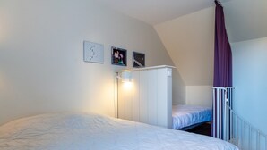 Un dormitorio con una cama litera, un armario blanco y un ventilador de techo.