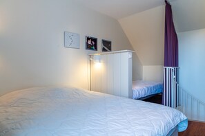 Ein Schlafzimmer mit Etagenbett, einem weißen Kleiderschrank und einem Deckenventilator.