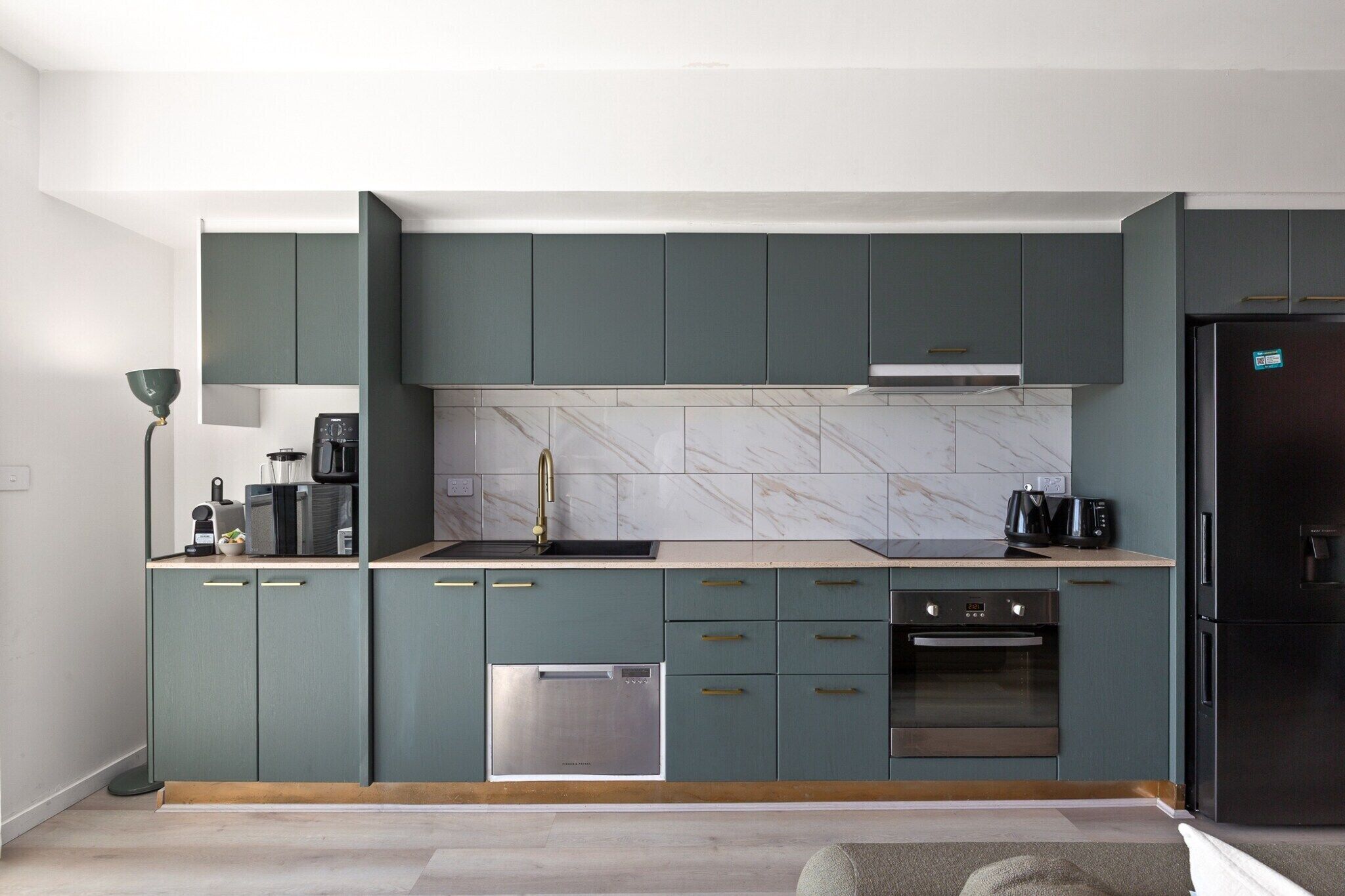 Une cuisine moderne avec des meubles de couleur turquoise, un lave-vaisselle en acier inoxydable et un réfrigérateur noir.