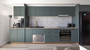 Una cocina moderna con armarios color turquesa, un lavavajillas de acero inoxidable y un refrigerador negro.