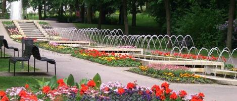 Un parque con una fuente, parterres de flores y bancos.