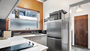 Uma cozinha moderna com geladeira de aço inoxidável, forno embutido e janela acima da pia.