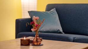 Una vela sobre una mesa con un florero y un libro.