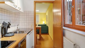 Cocina compacta con lavavajillas integrado, cafetera y ventana con vistas al exterior.