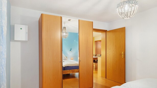 Un dormitorio con cama, armario de madera y candelabro.