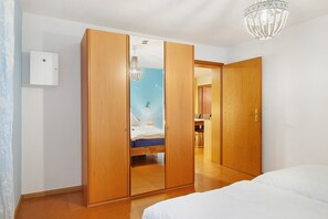 A bedroom with a bed, wooden wardrobe, and a chandelier.