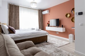 A modern bedroom with a bed, a TV, and a mounted air conditioner.