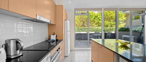 Una cocina moderna con armarios de madera, encimera negra y vistas del patio exterior.