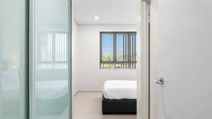 Un dormitorio moderno con cama, ventana con persianas y una puerta.
