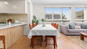Una cocina moderna con una mesa de comedor y sillas, un sofá y ventanas amplias.
