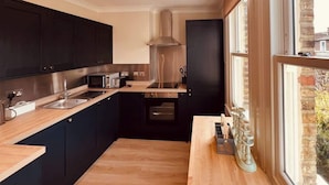 Una cucina moderna con mobili scuri, elettrodomestici in acciaio inossidabile e una finestra che offre vista all'esterno.