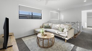 En moderne stue med sofa, sofabord og fjernsyn.