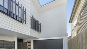 En moderne bygning med to etager, fladt tag, store vinduer og en garage.