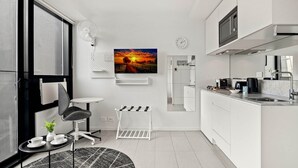 A modern kitchen with white cabinetry, a built-in microwave, and a coffee maker. - South Melbourne Apartment with Gym Access (South Melbourne)