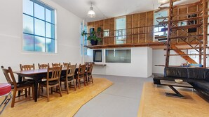 A modern interior with a dining area, a black leather sofa, and a wooden staircase. - Apartment "Atelier" with Private Terrace and Wi-Fi (Schopfheim)