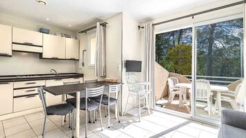 A modern kitchen with white cabinets, a dining table with chairs, and a large sliding glass door leading to an outdoor patio area.