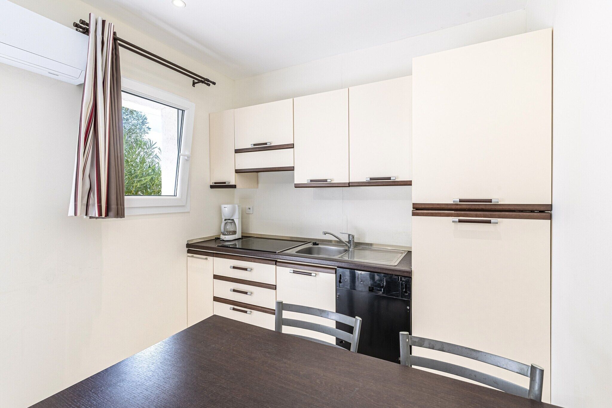 A compact kitchen with white cabinets, a stainless steel sink, and a coffee maker.