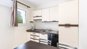 A compact kitchen with white cabinets, a stainless steel sink, and a coffee maker.