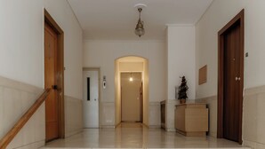 Un moderno vestíbulo de hotel con una escalera de mármol, puertas de madera y una lámpara central.